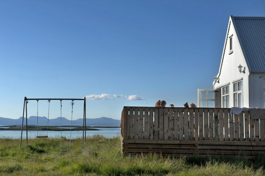 Vista sul mare e altalena in legno accanto a una casa bianca a Hólmavík, Islanda occidentale.

