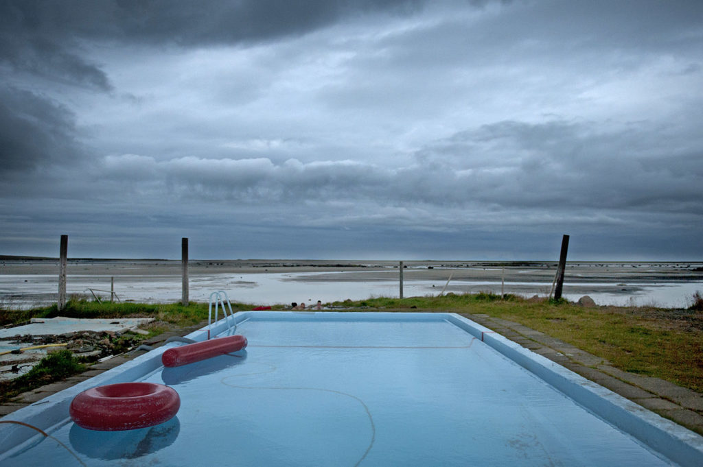 Piscina geotermica all’aperto con salvagenti rossi e vista sull’oceano a Drangsnes, Westfjords Islanda.