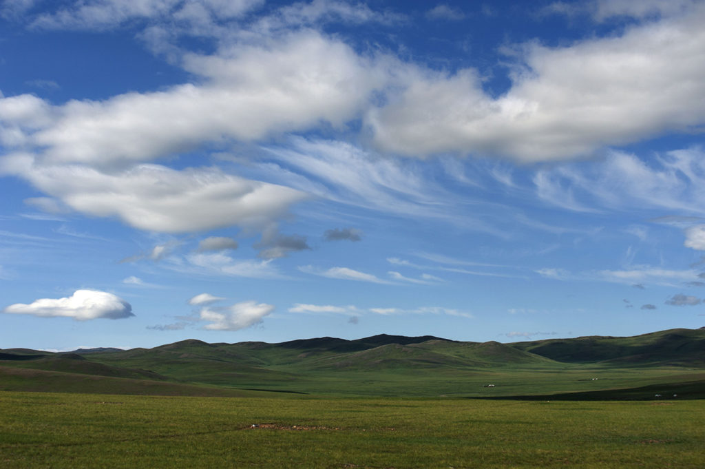 Steppa verde sotto un cielo azzurro con nuvole bianche nei pressi di Tsetserleg, Mongolia centrale
