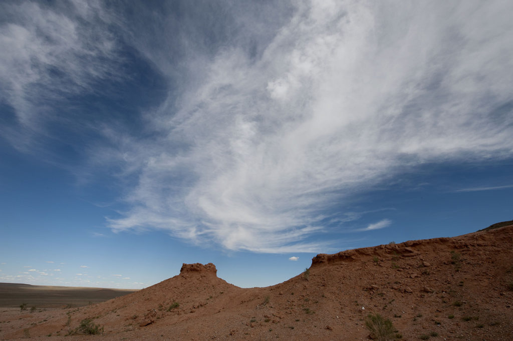 Formazione rocciosa nel deserto del Gobi con nuvole bianche in un cielo sereno
