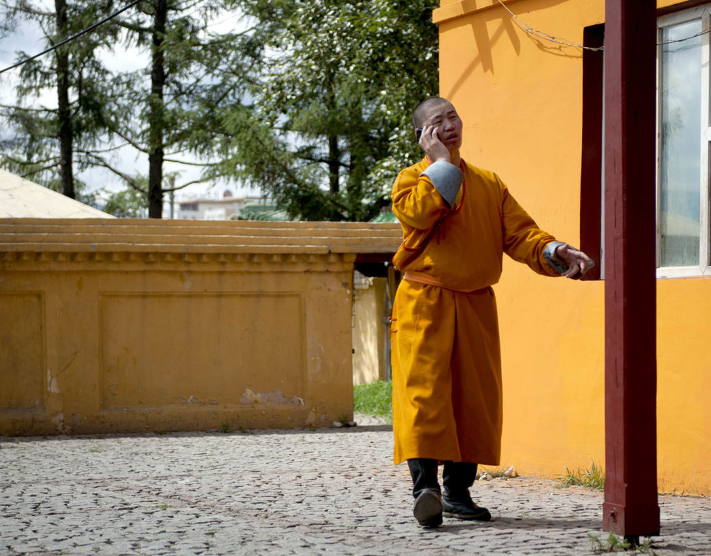 Monaco buddista Monaco buddhista anziano con abito arancione entra in un tempio a Ulaanbaatar
