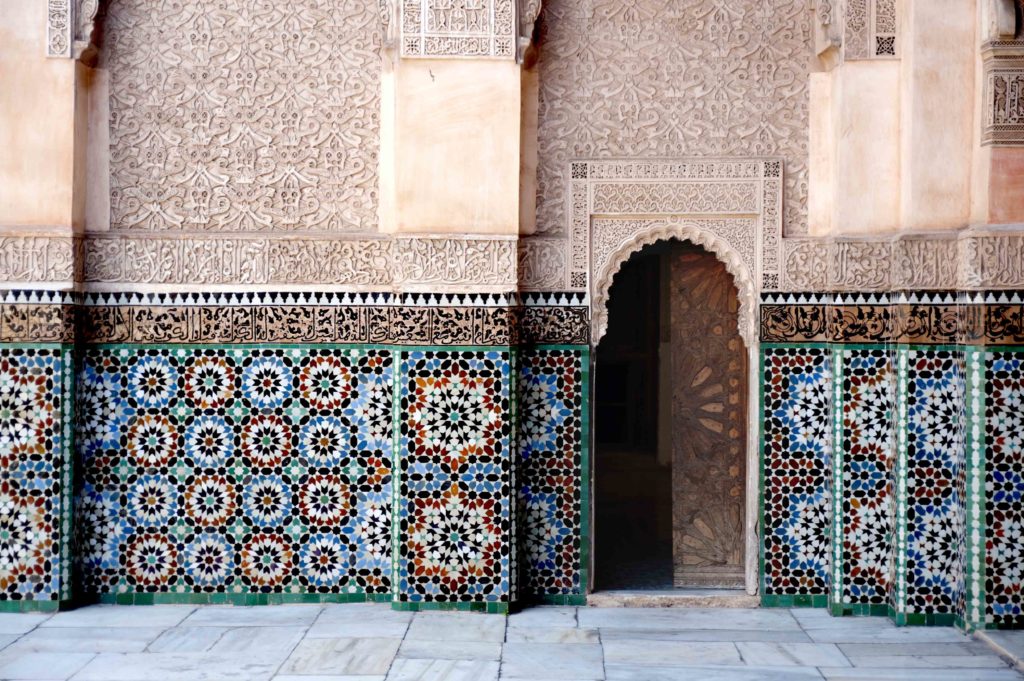 Dettaglio dell’ingresso della Medersa Ben Youssef a Marrakech con mosaici zellige colorati e architettura moresca.