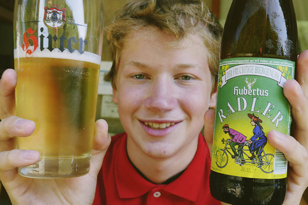 Ragazzo tiene in mano un bicchiere e una bottiglia di Radler nella Stazione e punto ristoro di Chiusaforte, Friuli Venezia Giulia