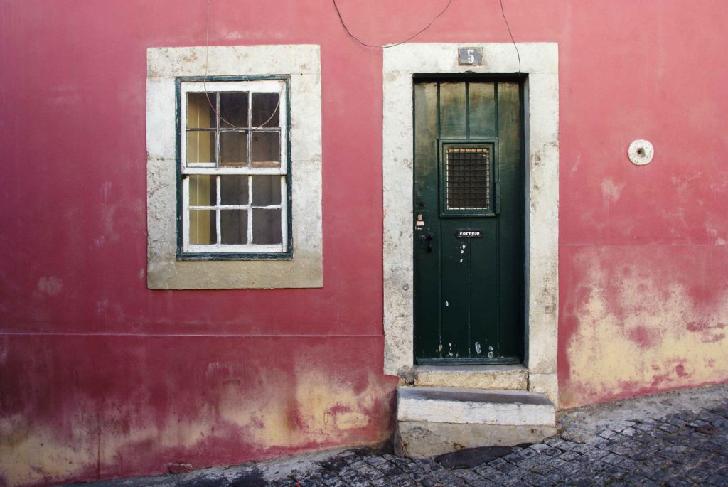 Porta verde e finestra su parete rossa nel quartiere Alfama di Lisbona