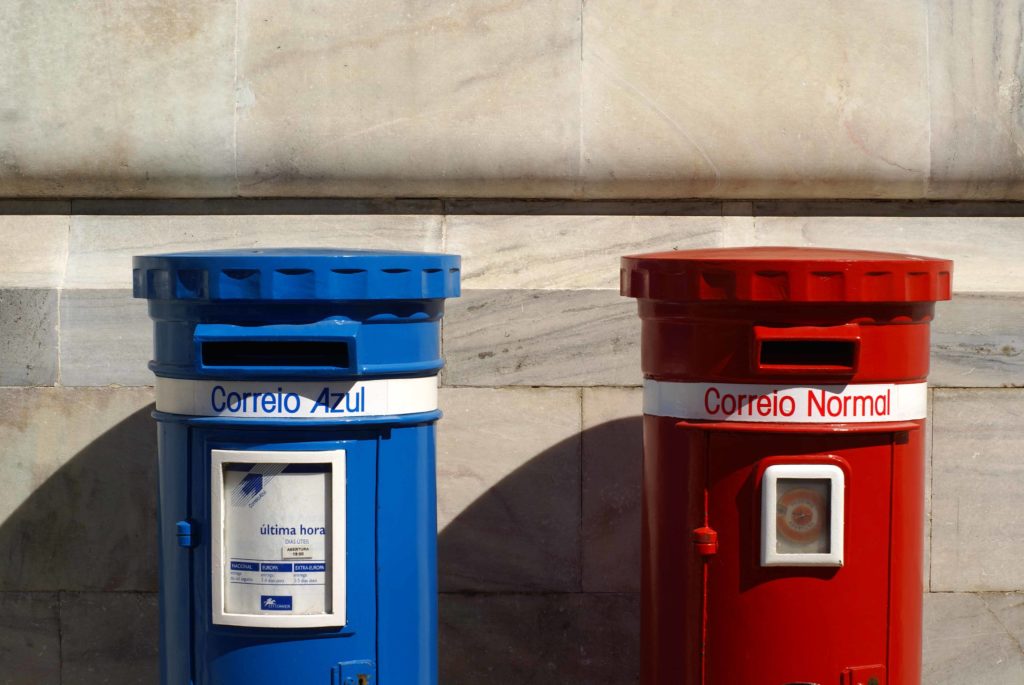 Cassette postali blu e rossa in stile vintage davanti a un edificio a Lisbona