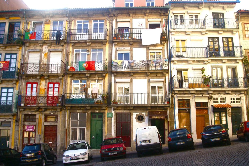 Facciata colorata di edificio storico con balconi e auto parcheggiate a Porto