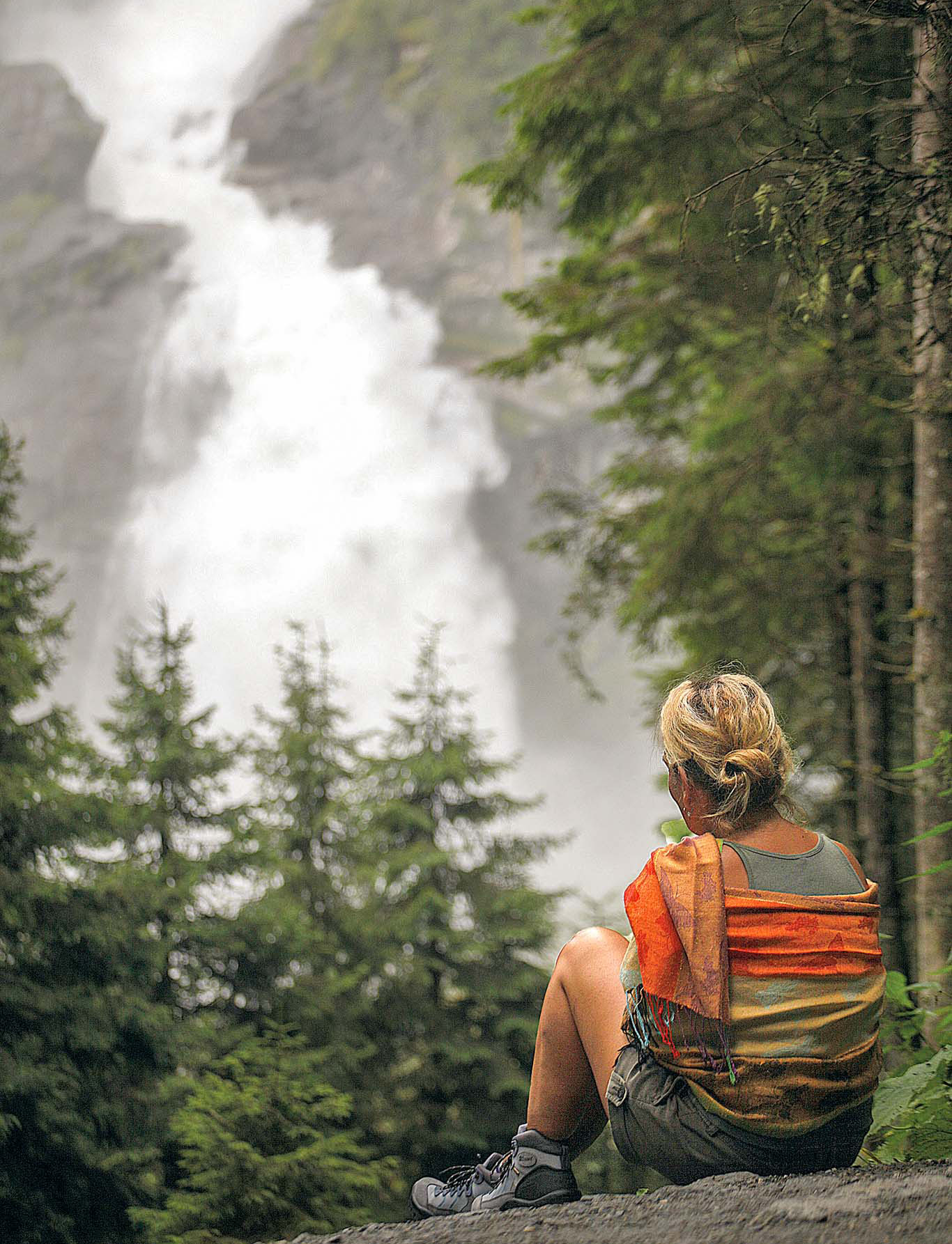 Donna seduta in un bosco vestita da trekking