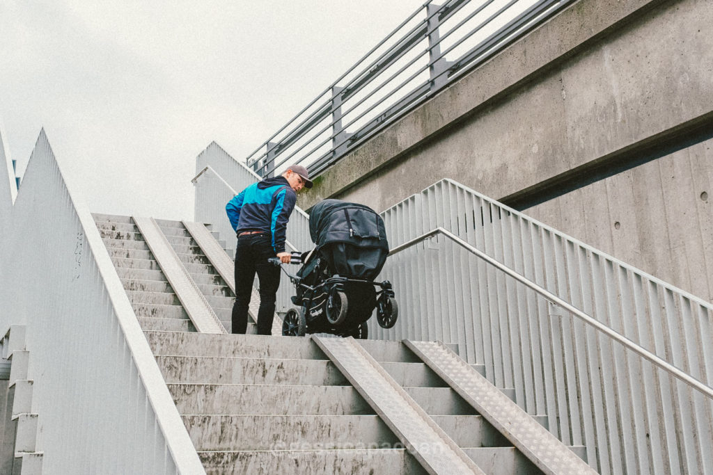 Ciclista che sale le scale con bicicletta lungo rampa urbana nel quartiere Ørestad di Copenaghen.