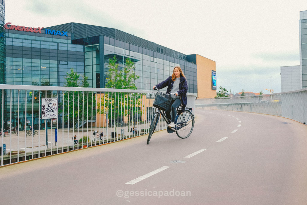 Ciclista su ponte pedonale moderno vicino alla Biblioteca Reale di Copenaghen, nota anche come Black Diamond.