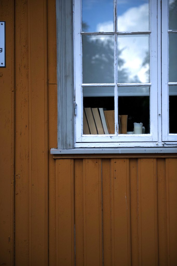 Finestra bianca su parete in legno arancione di una casa tradizionale a Trondheim, Norvegia.