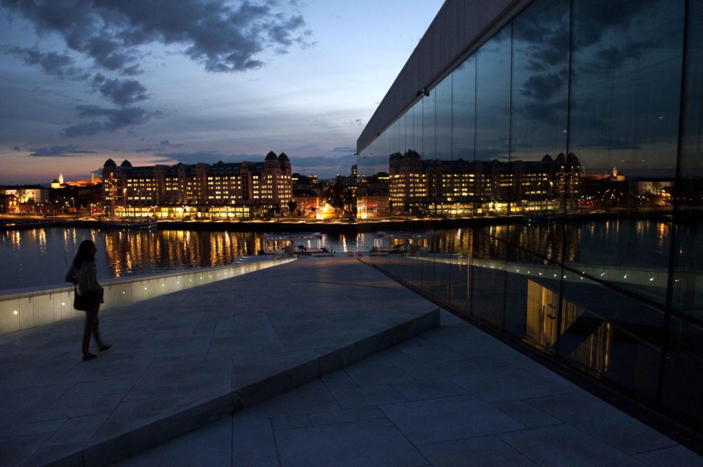 Riflessi della città e del cielo al tramonto sulle vetrate dell'Opera House di Oslo, Norvegia.