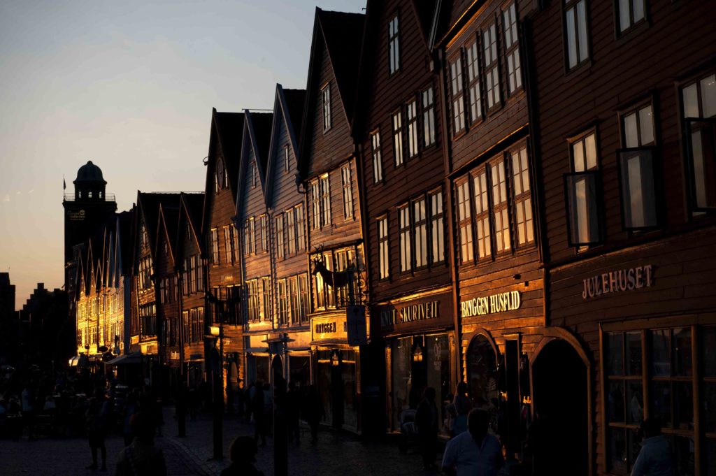 Facciate in legno del quartiere Bryggen a Bergen illuminate dalle luci del tramonto.