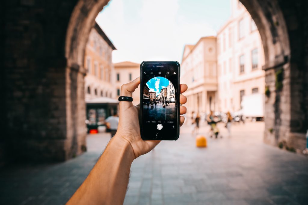 Mano che scatta una foto ad un centro storico con uno smartphone