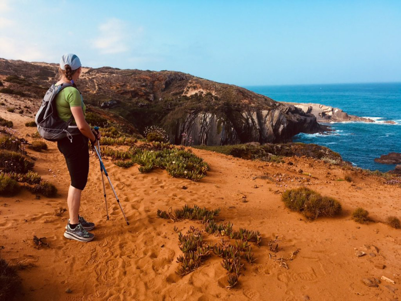 Donna con bastoncini da trekking guarda il panorama dal percorso lungo la Rota Vicentina in Portogallo