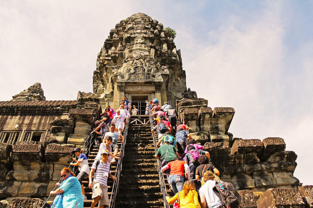 Visitatori salgono gli antichi gradini in pietra di un tempio di Angkor, Cambogia