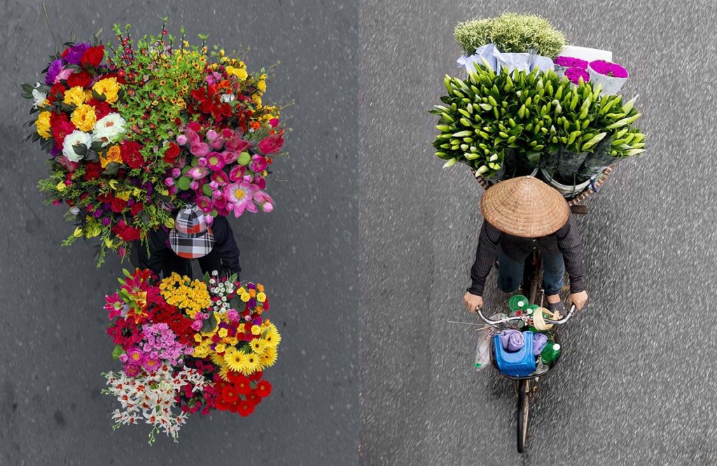 Venditori con biciclette cariche di fiori colorati per le strade di Hanoi, Vietnam.