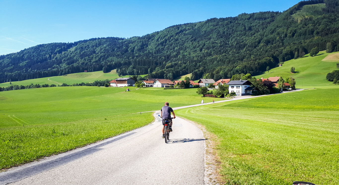 Ciclista pedala lungo la ciclabile nel salisburghese circondato da prati e montagne verdi