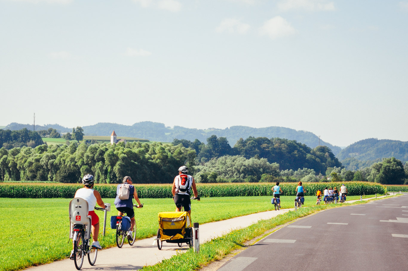 Famiglia in bicicletta su pista ciclabile in mezzo alla natura in vacanza con Girolibero