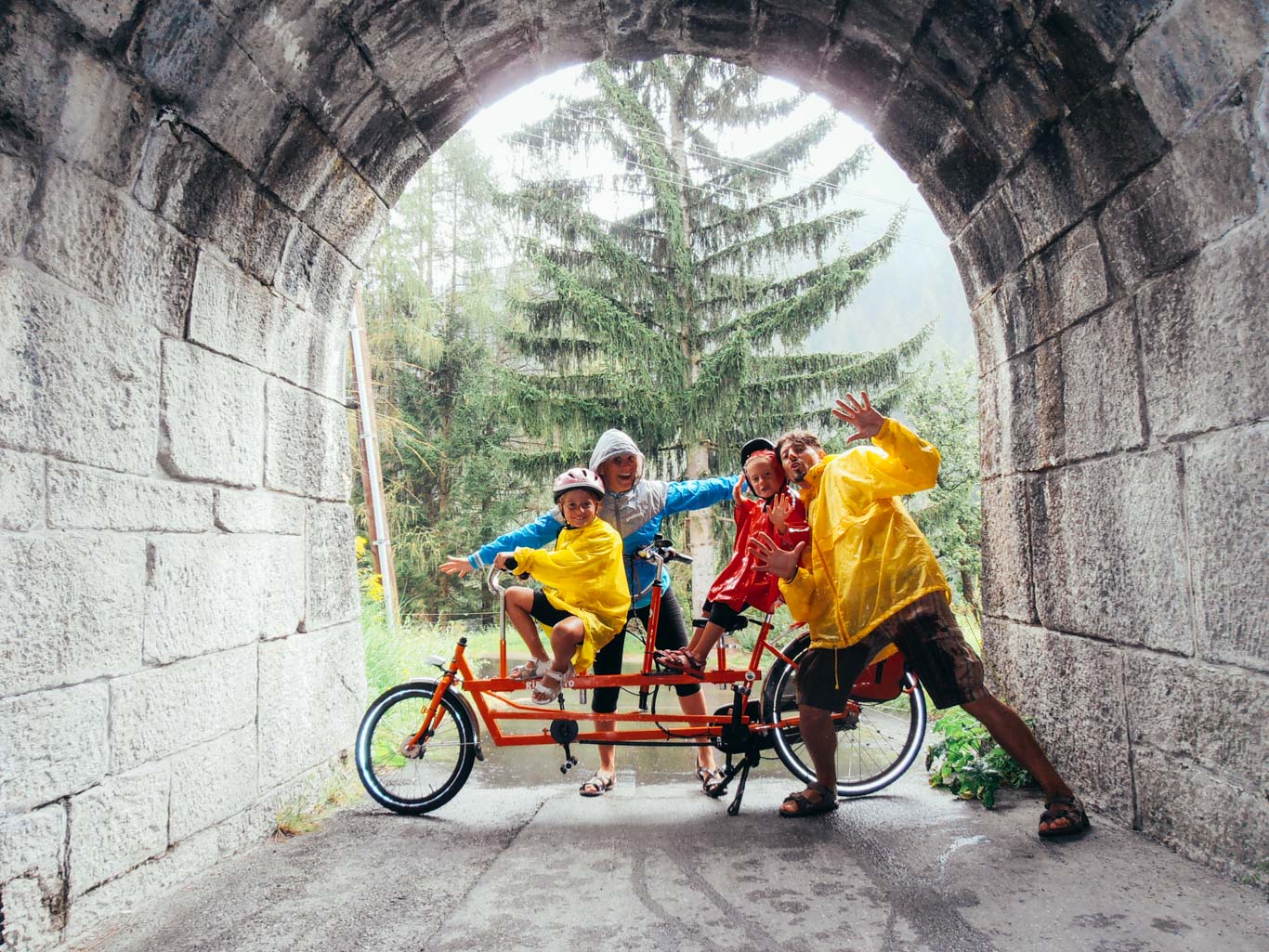 Famiglia in bicicletta sotto la pioggia, ben equipaggiata