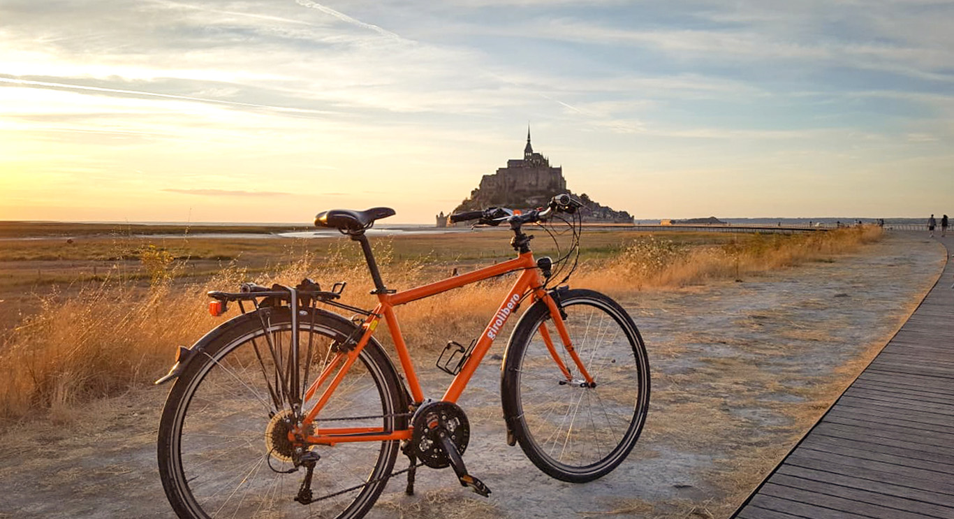 Mont St Michel nell sfondo e bici arancione Girolibero davanti