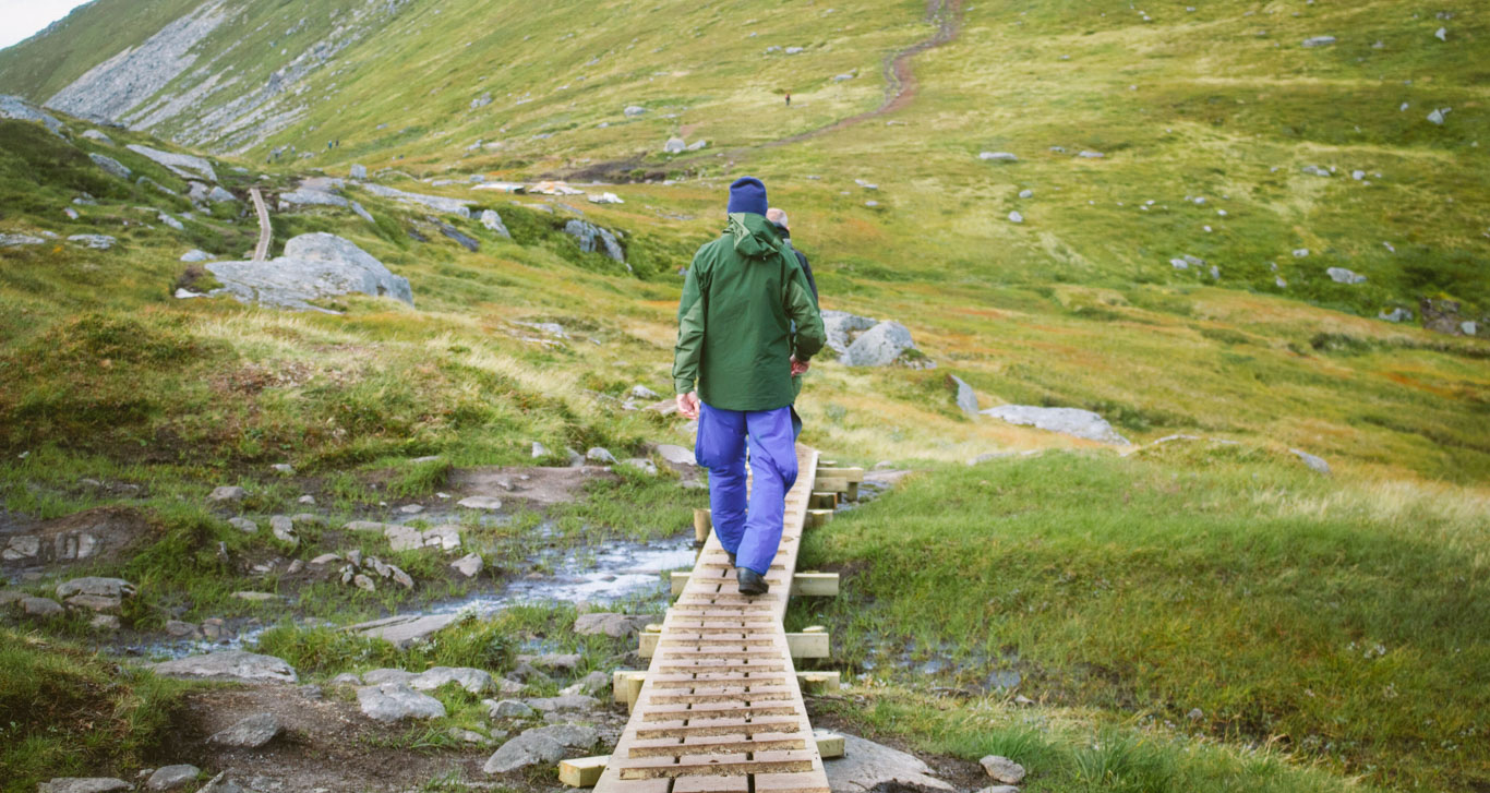 Uomo in abiti sportivi cammina su una passerella in un paesaggio di montagna