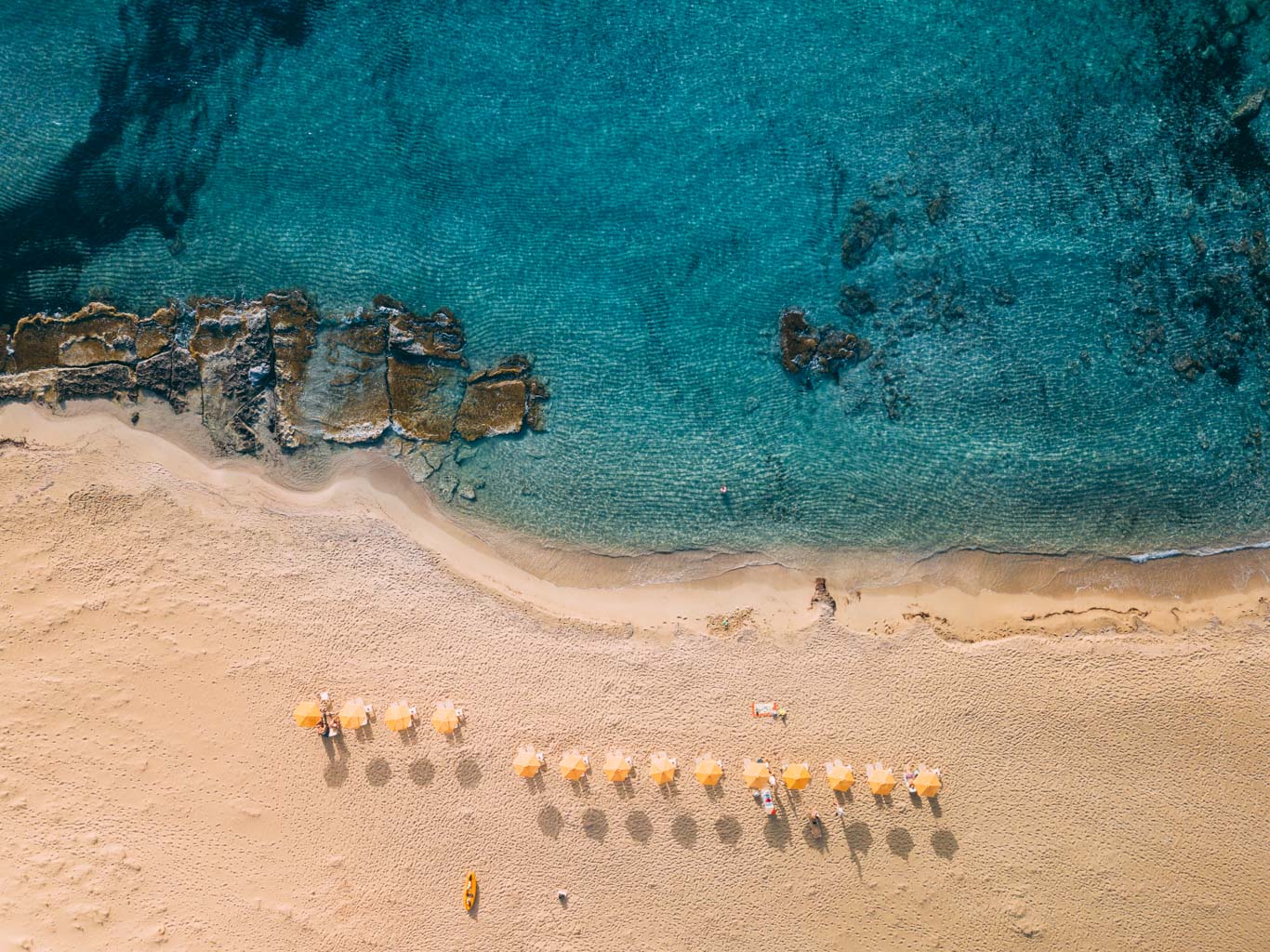 Spiaggia di Creta: mare turchese e spiaggia con pochissimi ombrelloni gialli