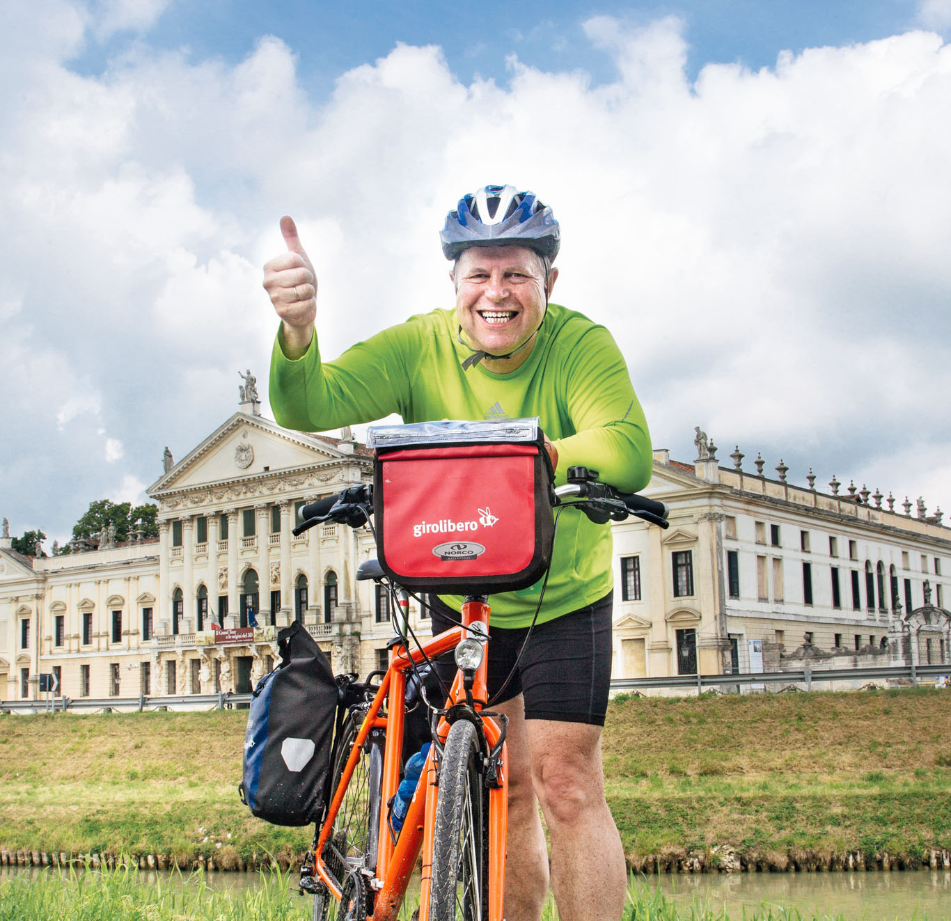 Happy cyclist with orange Girolibero bike along the Brenta bike path