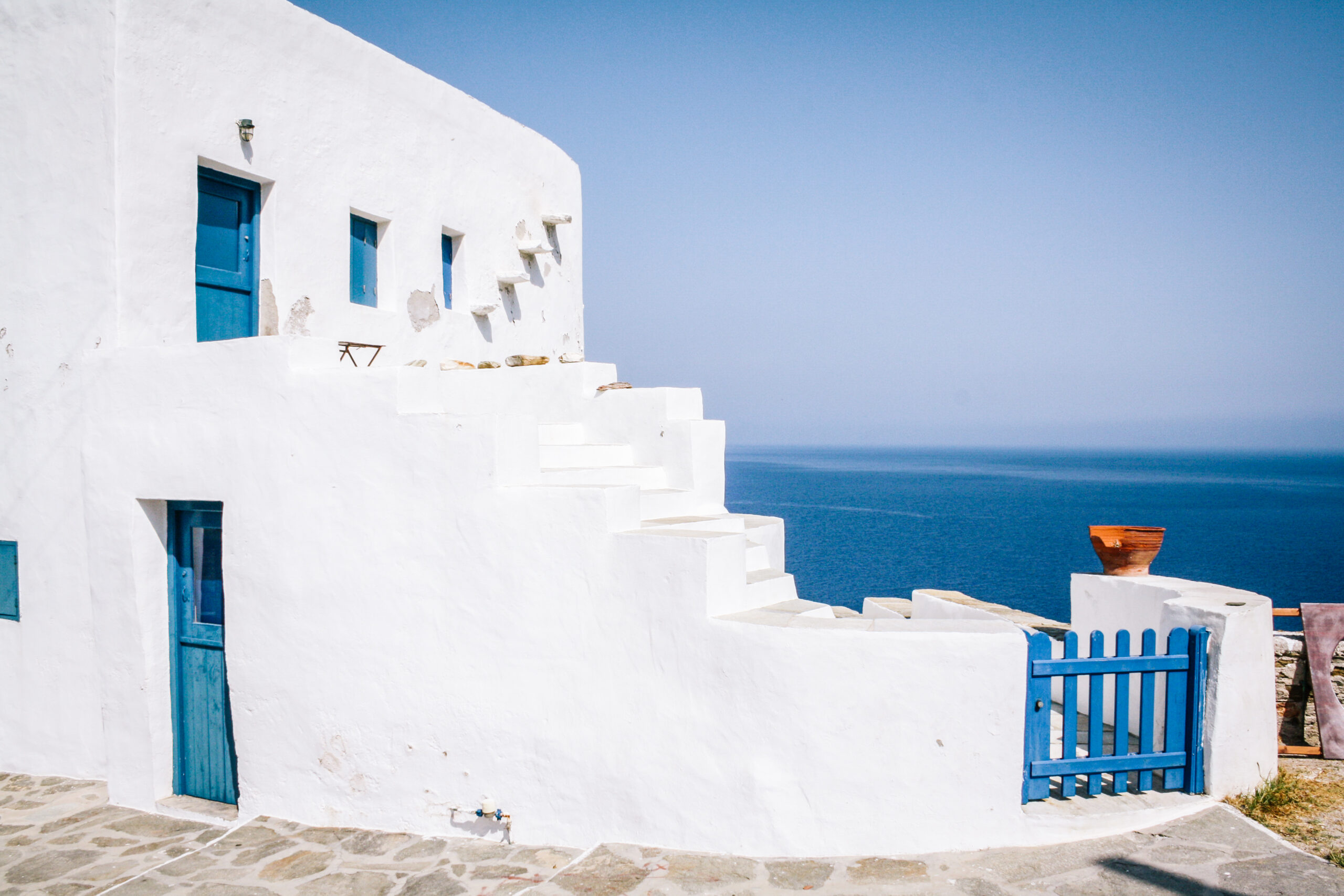 Tipica casa bianca greca con infissi blu e mare sullo sfondo