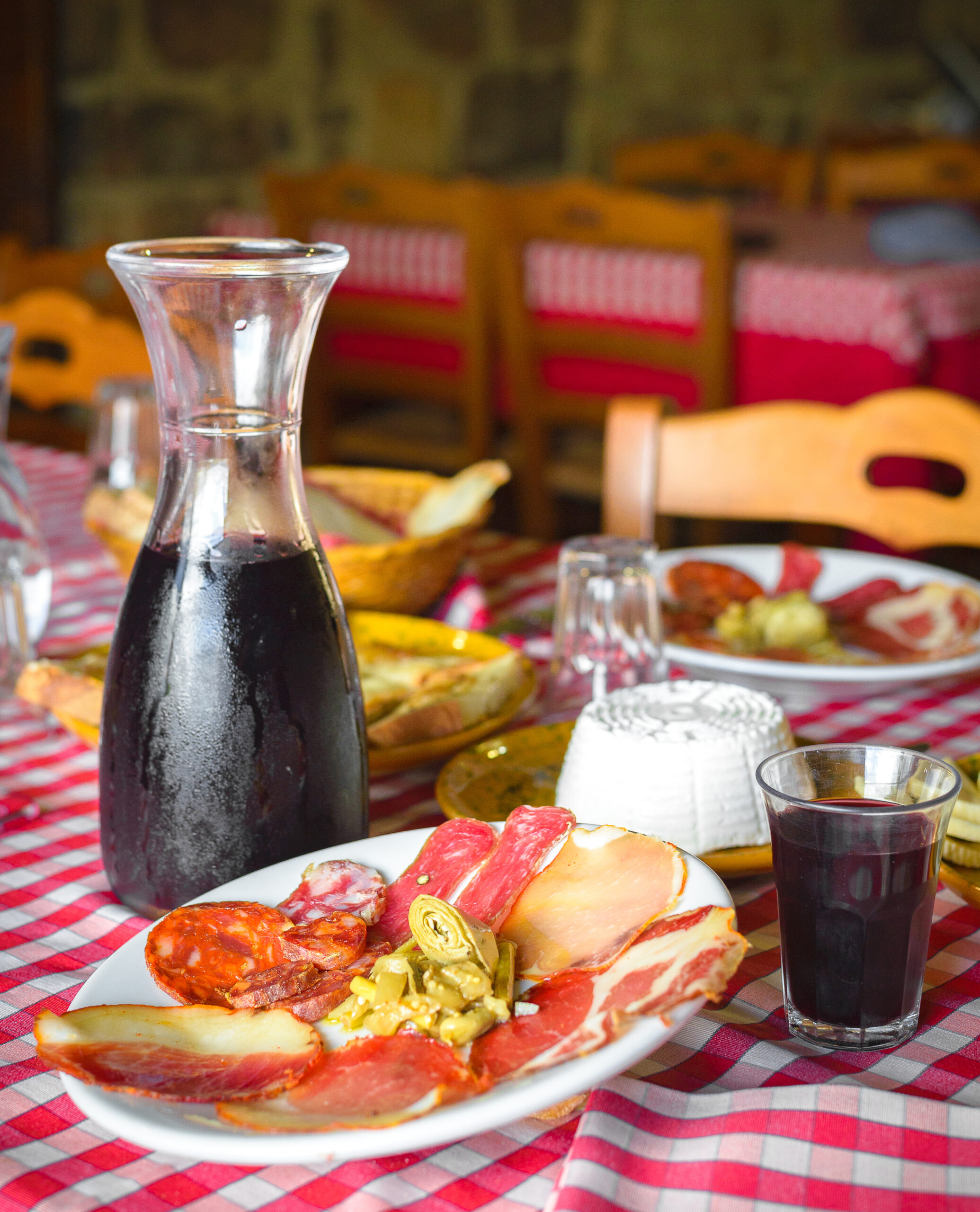 Tavola imbandita con piatto di salumi e sottaceti, ricotta e del vino rosso