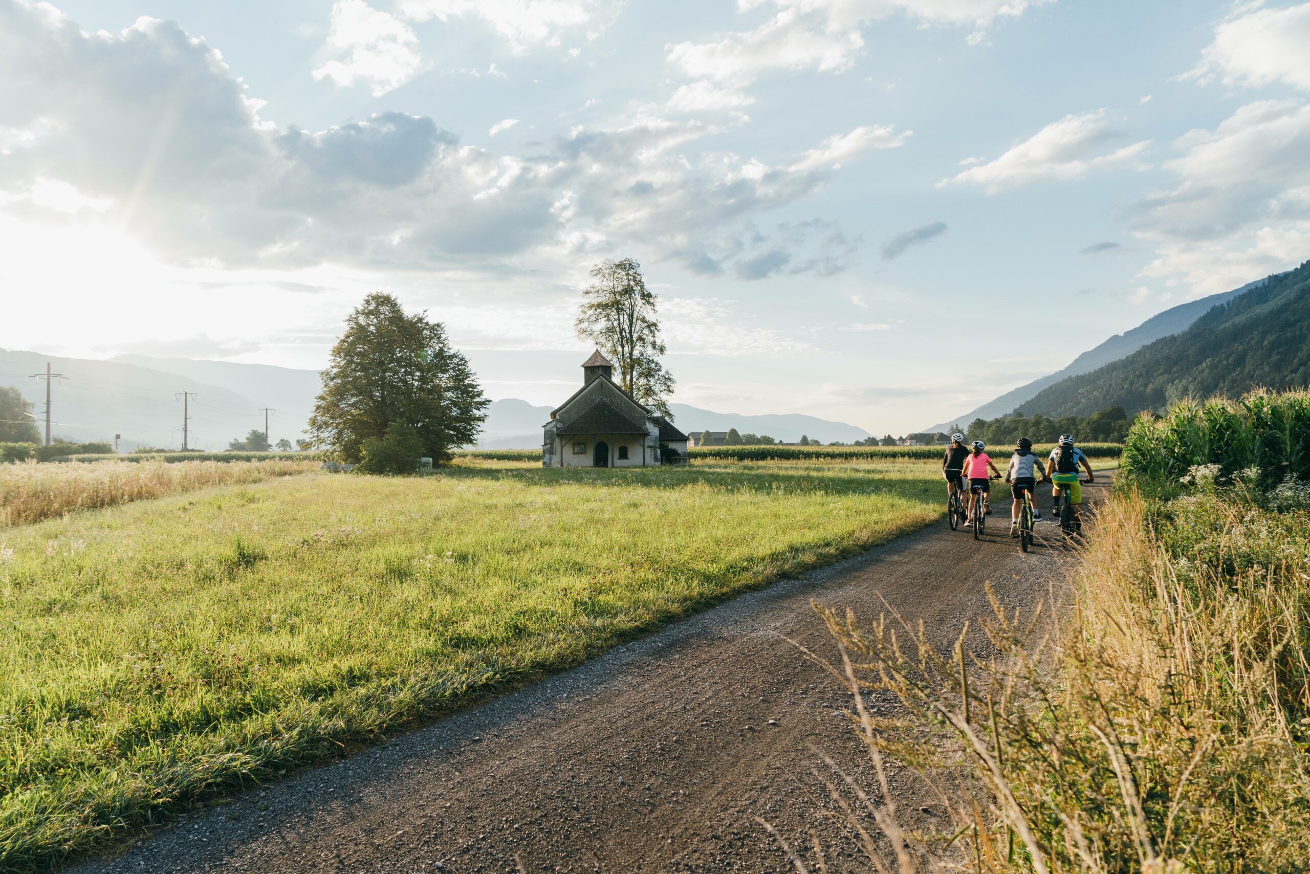 Ciclisti che pedalano in una ciclabile su strada di campagna in Carinzia in una giornata soleggiata