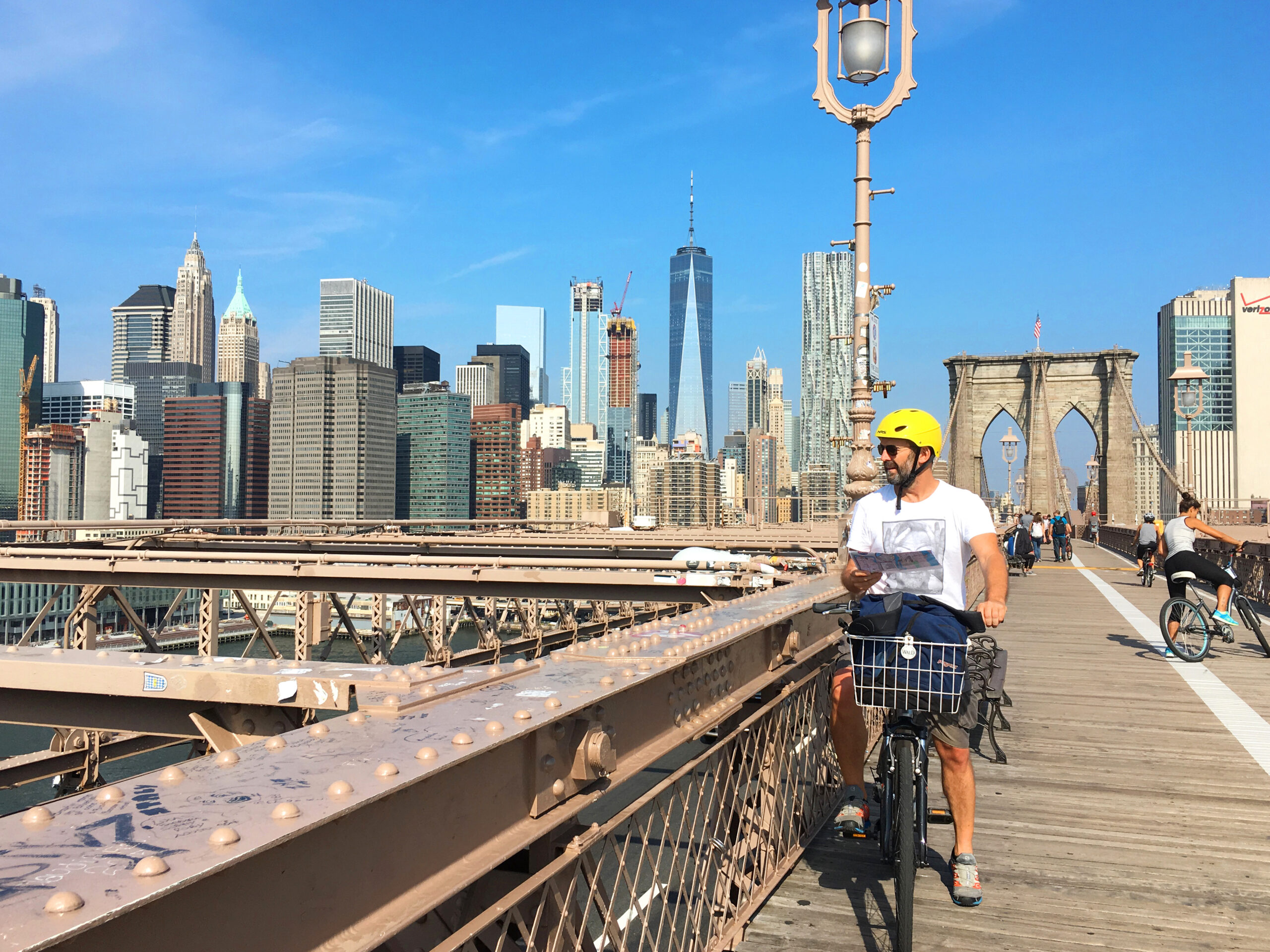 Uomo in bicicletta su un ponte e grattacieli sullo sfondo, viaggio a New York in bicicletta