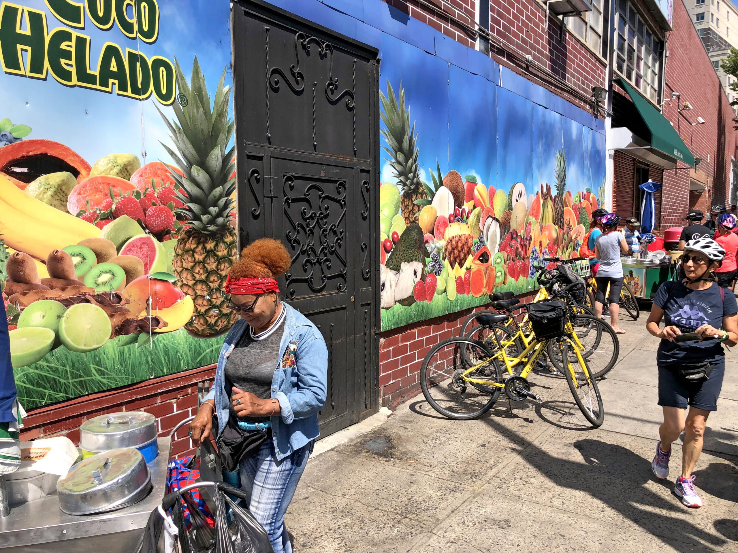 Marciapiede con biciclette, murales colorato e persone che camminano