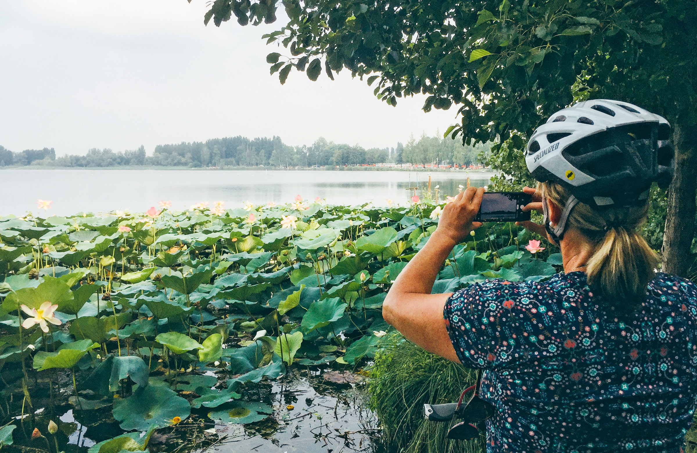 Woman taking smartphone photos of water lilies