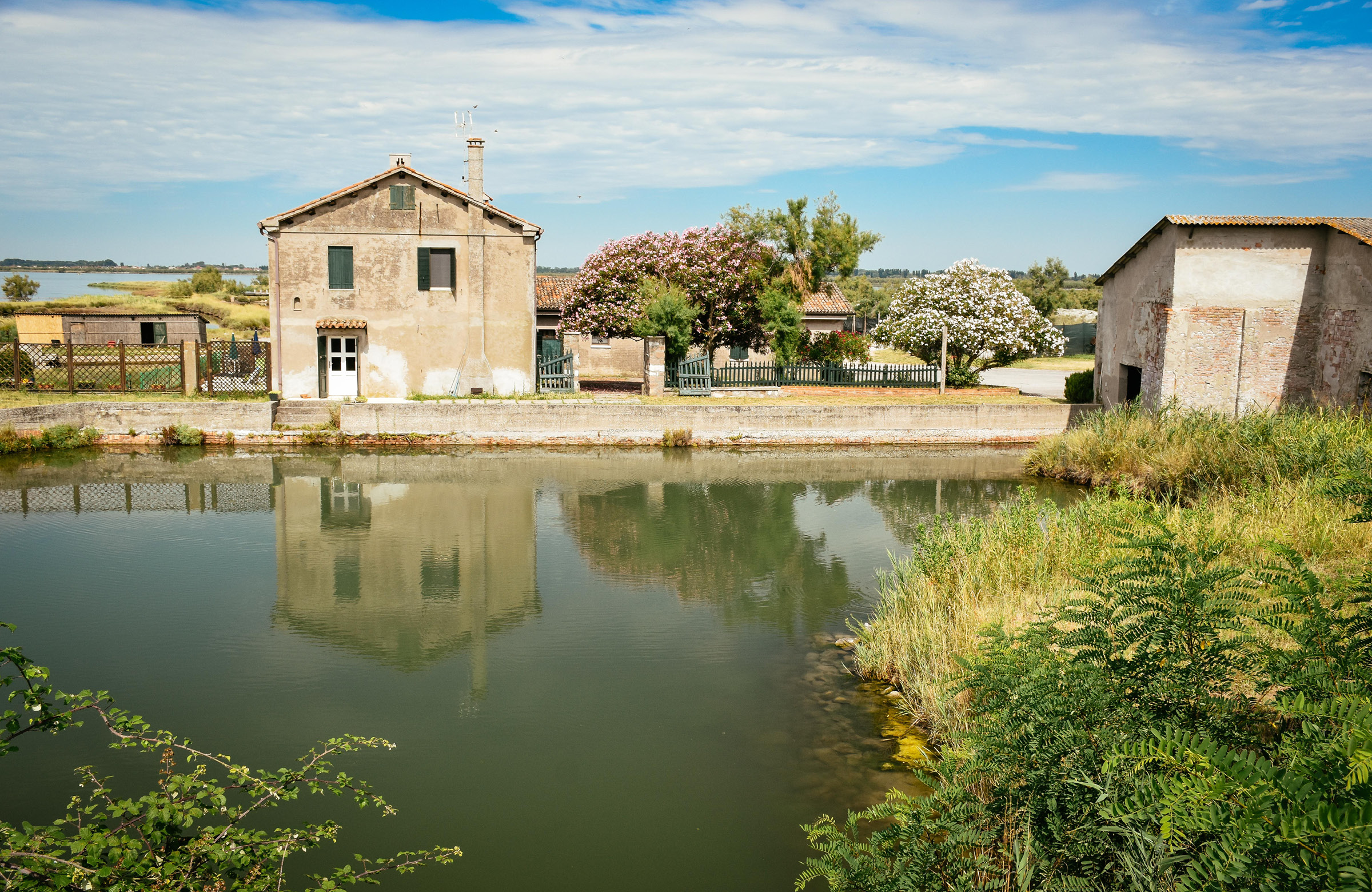 Lagoon landscape with a large house and a fenced garden