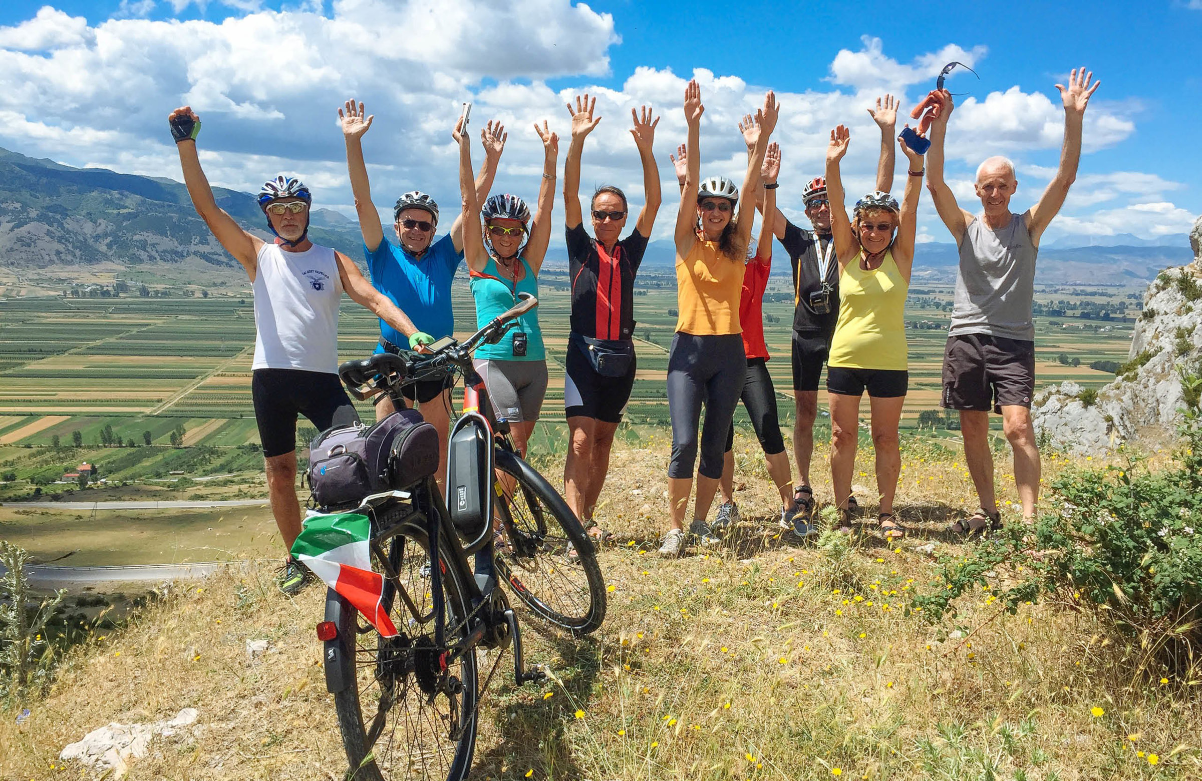 Group of cyclists with hands up and electric bike in front.