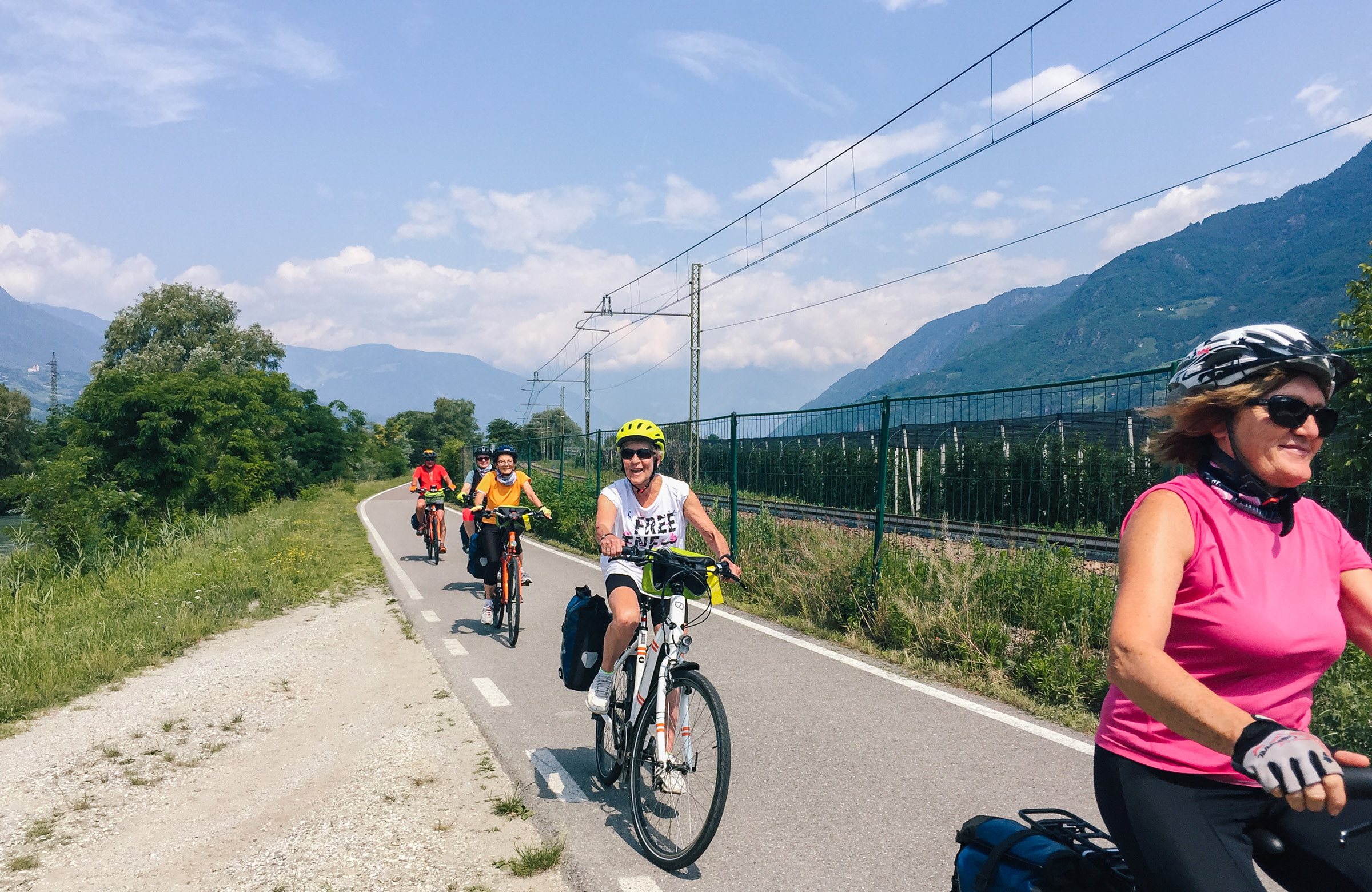 Smiling group of cyclists pedaling along a bicycle path.