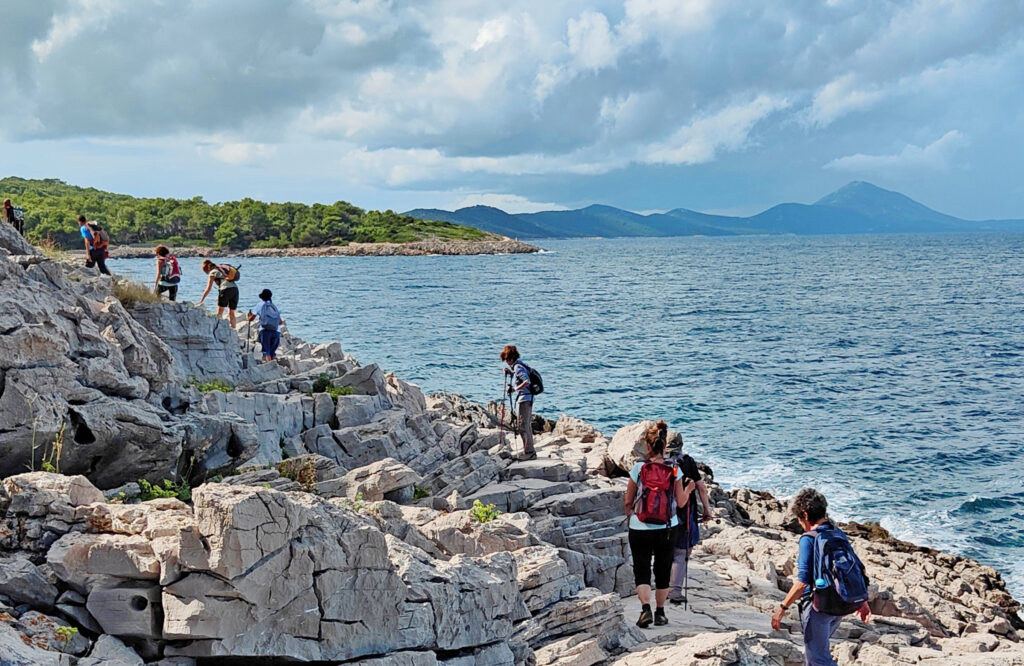 Gruppo di camminatori che fanno trekking lungo la scogliera che si affaccia sul mare a Lussino in Croazia.