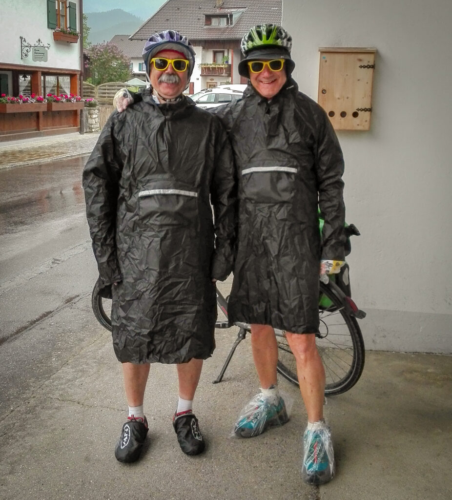 Two smiling cyclists wearing raincoats to protect themselves from the rain