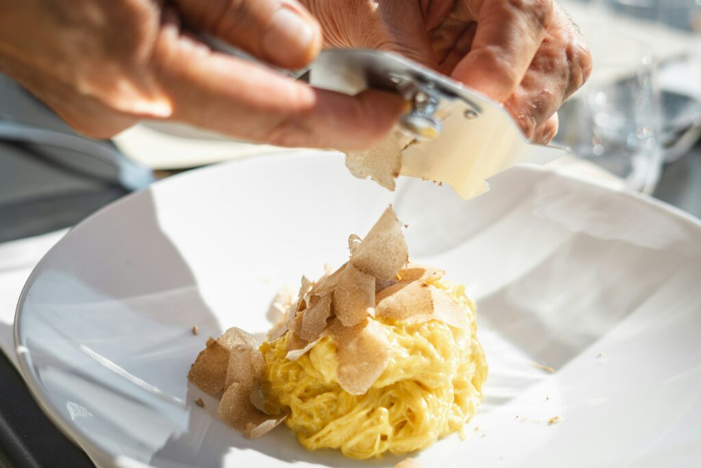 Fresh tagliatelle being grated with Parmesan, Italian cuisine