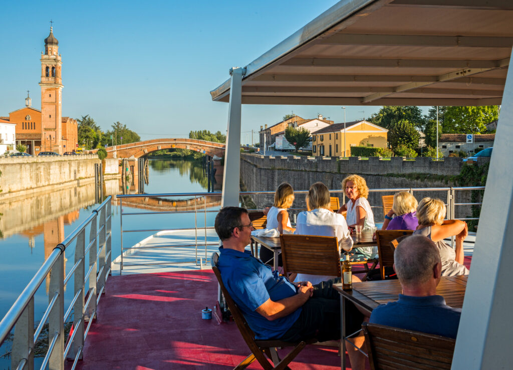 Cyclists dining on the deck of a hotel barge, bike and barge tour Italy