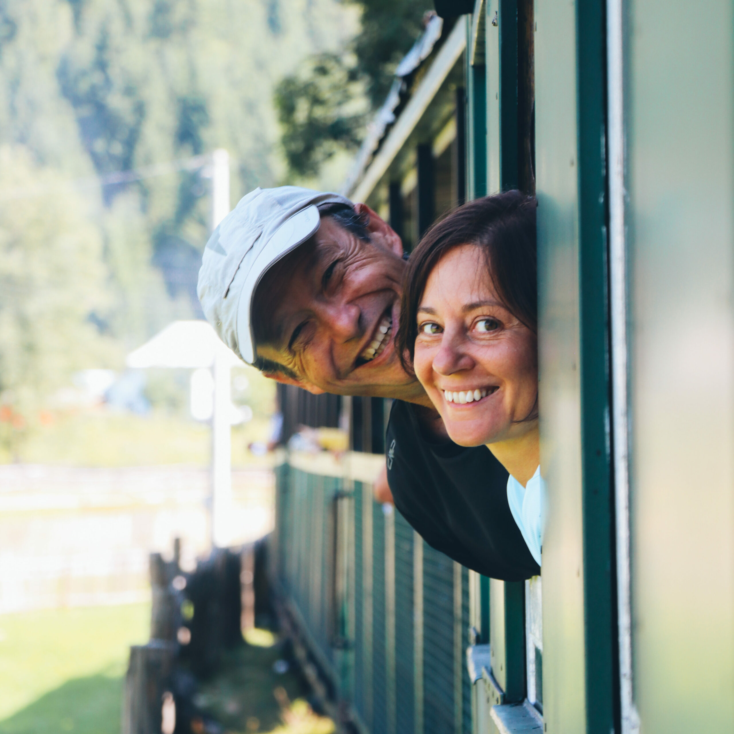 Persone sorridenti affacciate dai finestrini di un treno turistico nelle montagne della Romania